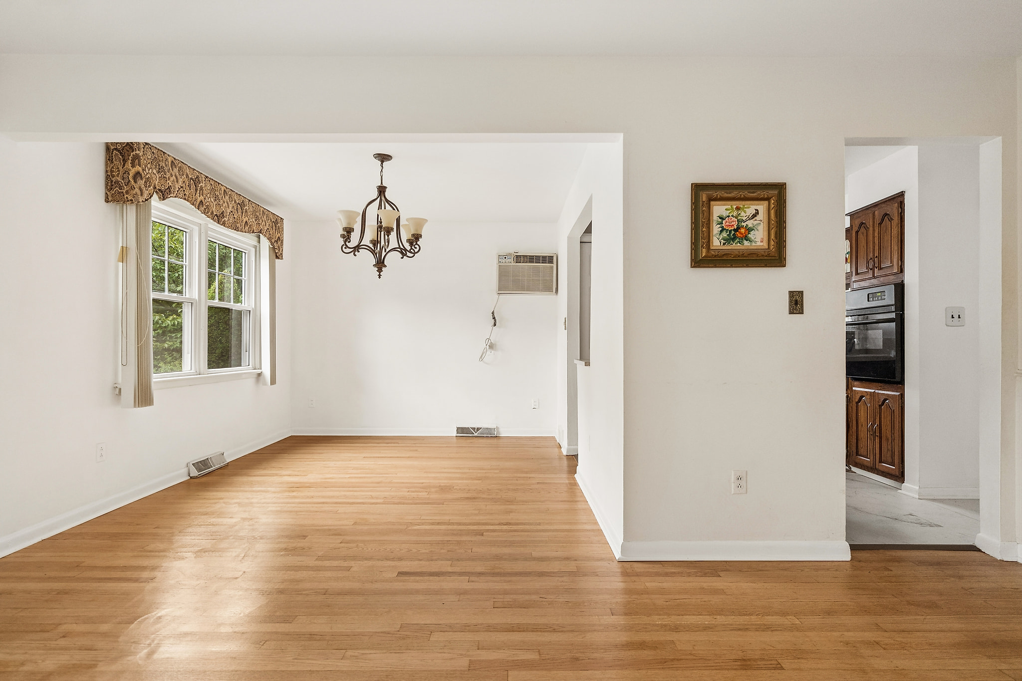 This should be the dining room view with a table perfectly under the hanging chandelier. Add some simple aesthetics that fit the space with the table. Match the current style of the home but keep it clean.